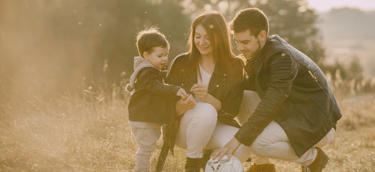 A cheerful family bonding outdoors with a soccer ball, enjoying a sunny day in the grass.