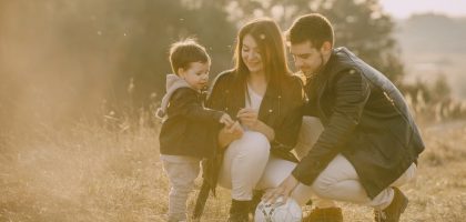 A cheerful family bonding outdoors with a soccer ball, enjoying a sunny day in the grass.