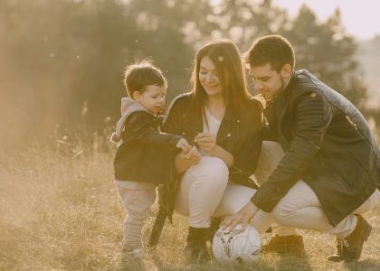 A cheerful family bonding outdoors with a soccer ball, enjoying a sunny day in the grass.